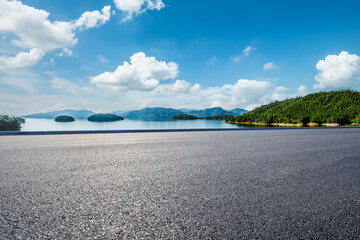 Asphalt highway road and lake with mountains nature landscape on a sunny day. Beautiful coastline...