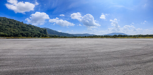 Asphalt road square and green mountains with sky clouds background. panoramic view.