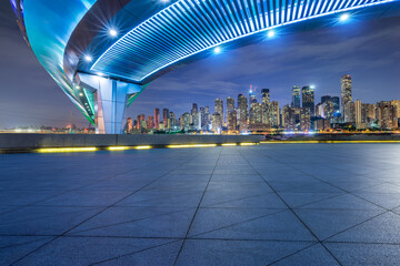 Empty square floor and pedestrian bridge with modern city buildings at night in Chongqing