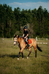 A teenage boy in a helmet learns horse riding in the summer, the instructor teaches the child...