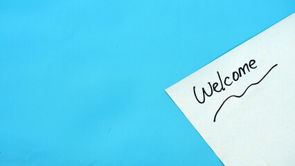 Welcome text on white paper with blue background copy space