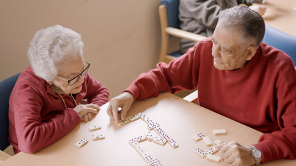 Senior man playing dominoes with old friend in geriatric