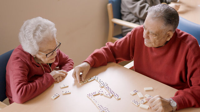 Senior man playing dominoes with old friend in geriatric - Powered by Adobe