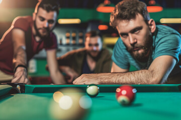  Pub atmosphere photo. young handsome men playing billiard with friends, aiming for billiards ball in a bar at night out