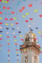 Bajo el Encanto Festivo: Banderines de Colores ondeando frente a una Majestuosa Torre de Reloj
