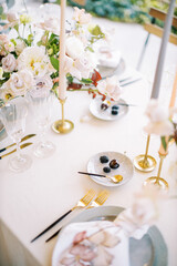 Berries lie on saucers with teaspoons on a set table near bouquets of flowers