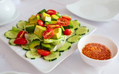 Healthy vegetarian dish, vegetable salad with fresh tomato, cucumber and avocado. Fresh summer salad with avocado
