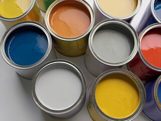 Top view of open paint cans with various colors on a white surface