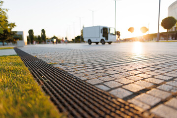 street paved with stone blocks with white lines. Shallow depth of field. City ​​and park on background.