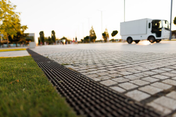 street paved with stone blocks with white lines. Shallow depth of field. City ​​and park on background.