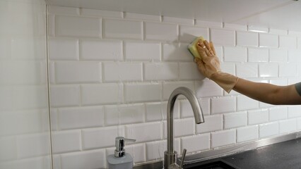 Woman cleaning the kitchen with a steam cleaner, hands close-up. A woman's hand cleans the tiles...