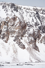 Detail of a steep and snowy mountain slope in Berlevåg with a car at the base of the mountain,...