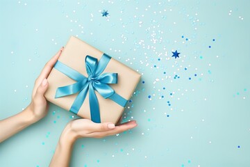 Hands holding gift with blue ribbon on blue
