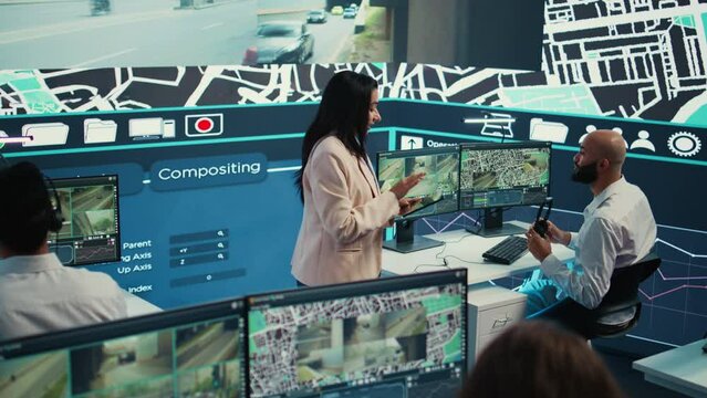 Indian manager and her team monitoring their delivery cars in traffic, following the best routes through surveillance CCTV system to guide the couriers. Control center map navigation. Camera B.