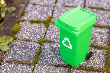 Miniature green garbage bin for biodegradable waste, standing on the sidewalk, garbage segregation concept
