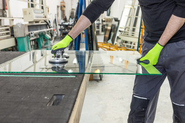 A glazier lifts the glass in the factory using a special glass suction cup.