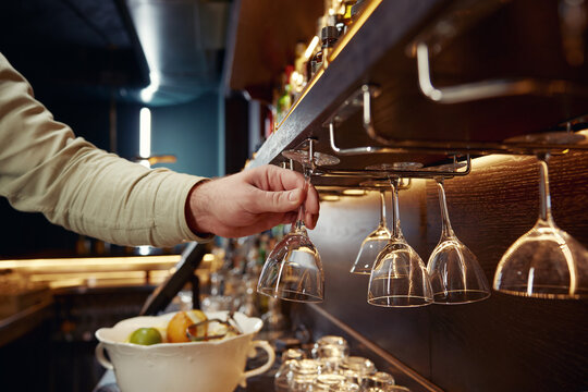 Closeup hand of bartender taking clean glass for cocktail