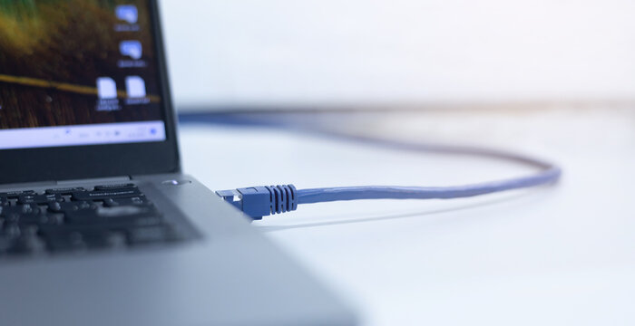 close up on laptop port interface with blue an cable connected to transfer bandwidth and usage internet data to global network for internet technology transmission service concept