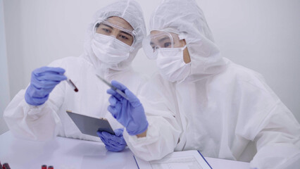 Two scientists dressed in protective gear examining samples and discussing results in a high-tech laboratory setting.
