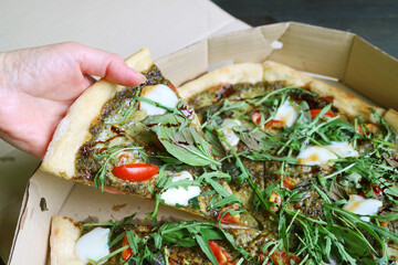 Hand Picking a Slice of Delectable Arugula Balsamic Pizza from Paper Box