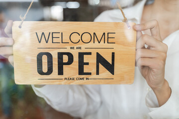 Small business owner smiling while turning the sign for open store.