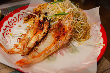 Jumbo King Prawn Pad Thai with Bean Sprouts and Crushed Peanuts on a Vibrant Ceramic Plate