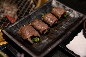 Exquisite Beef Negimaki with scallions, elegantly presented on a sleek black plate, showcasing the traditional Japanese dish in a refined setting