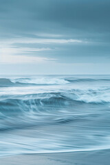 Fototapeta premium A tranquil and serene scene of sky blue and soft gray waves, merging gently in a calming dance that evokes the peacefulness of an overcast day at the beach.