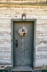 An old front door to a log house with a lantern at the entrance.