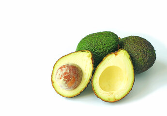 Heap of cut in half fresh ripe avocado and whole fruits isolated on white background