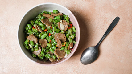Stir fry the beans in a bowl placed on the table with a tablespoon.