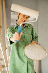 Joyful woman paints walls at home