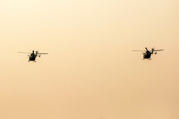 Fototapeta na wymiar Two silhouette helicopters are flying on isolated dawn sky