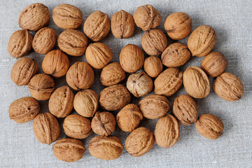walnuts in shell on gray linen fabric close-up.