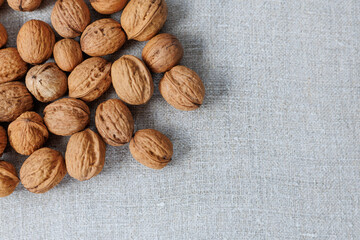 walnuts in shell on gray linen fabric close-up.