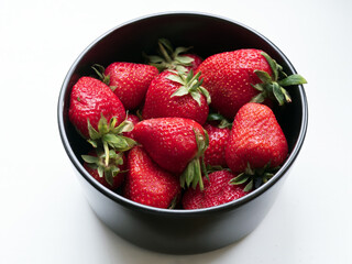 Large strawberry in a black bowl. Close-up