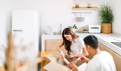 couple storing kitchen tools new house together. lover unpack box decorating new home kitchen support each other. wife and husband picking tools in the box relocating to new living location kitchen