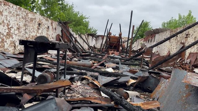 Bombed and burned industrial workshop of plant without roof with walls made of shell rock damaged by shrapnel from an exploding shell. War in Ukraine