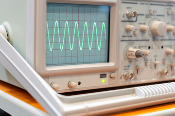 Green sine waves on the screen of a multi-button oscilloscope