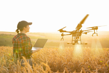 Woman farmer controls drone sprayer with a tablet. Smart farming and precision agriculture.