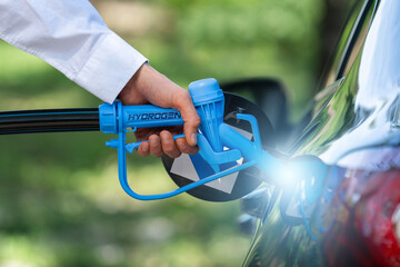 Man holds a hydrogen fueling nozzle. Refueling car with hydrogen fuel. Concept.