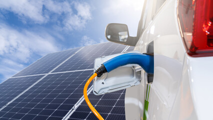 Close up of electric car with a connected charging cable on the background of solar panels..