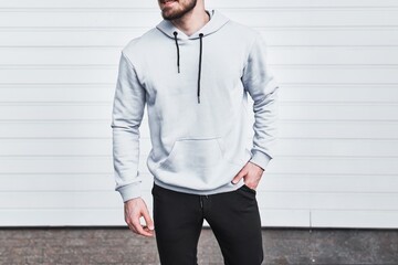 Man in a white hoodie poses for a mock-up design. A fashion template for print and branding. An...