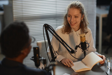 High angle view of cheerful Caucasian female host talking to unrecognizable guest sitting with...