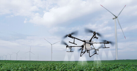Drone sprayer flies over the agricultural field. Wind turbines on a horizon.Drone sprayer flies...