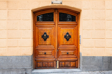 A wooden door with a handle in the wall of the house in close-up - Madrid, Spain