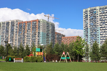 New houses of residential district and construction cranes, view from children playground. Building...