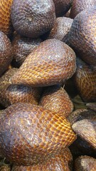 Close up of a pile of snake fruit being sold at the market in the background.