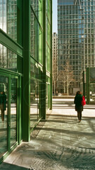 A woman walks down a sidewalk in front of a green building