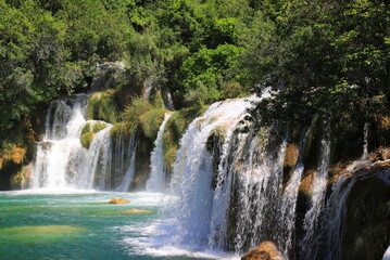 Fototapeta premium cascade waterfall among large stones in Krka Landscape Park, Croatia in spring or summer. The big beautiful Croatian waterfalls, mountains and nature.
